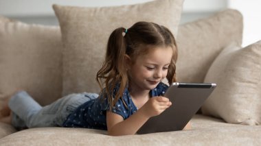 Küçük beyaz çocuk evde tablet kullanıyor.