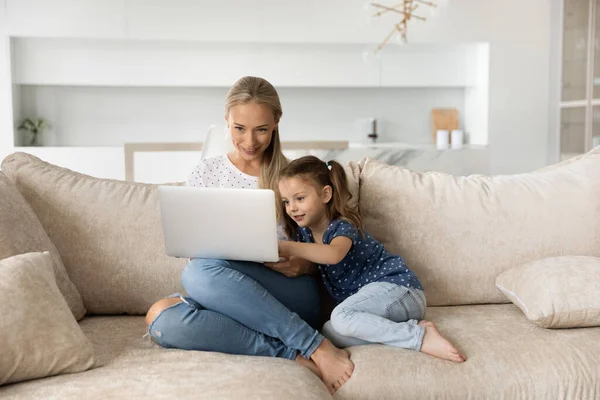 Glückliche junge Mutter und kleine Tochter nutzen Laptop — Stockfoto