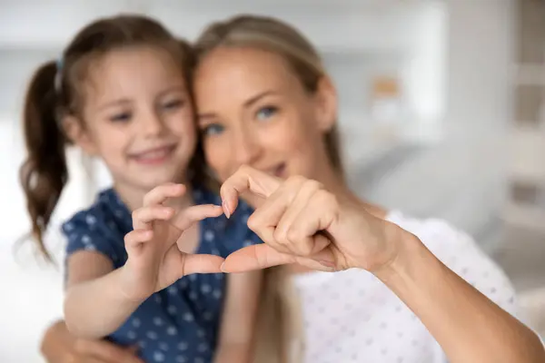 Primer plano de feliz mamá e hija hacen gesto de corazón —  Fotos de Stock