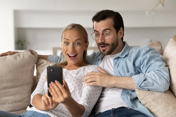 Удивительная пара шокирована неожиданной сделкой на смартфоне — стоковое фото