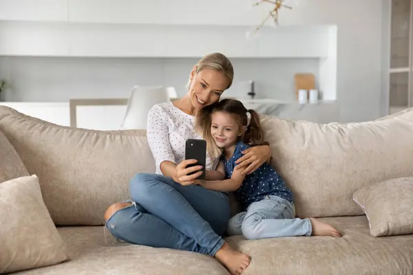 Happy young mom and little daughter use cellphone — Stock Photo, Image