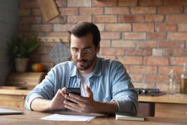 Genç beyaz adam internette akıllı telefon mesajı kullanıyor.