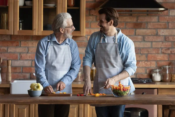 Smiling adult son and old father cook together — Stock Photo, Image