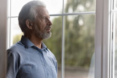 Mutsuz yaşlı bir adam uzaklardan kayıp görünüyor.