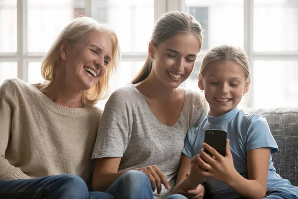 Happy three generations of women use smartphone gadget