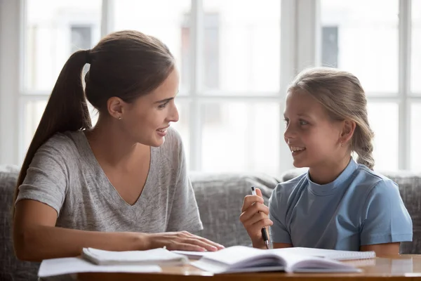 Sonriente joven mamá y adolescente hija hablar haciendo tarea —  Fotos de Stock