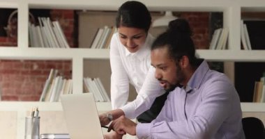 Çeşitli meslektaşlar laptop ekranına bakarak işbirliği projesi üzerinde çalışıyorlar