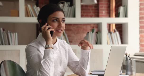 Indická podnikatelka sedí za stolem mluvit s klientem po telefonu — Stock video