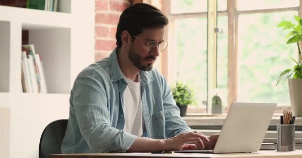 Hombre sentarse en interiores usando el ordenador portátil leyendo grandes noticias se siente emocionado — Vídeo de stock