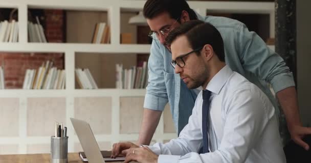 I compagni di lavoro seri discutono il progetto collaborativo usando il computer portatile in ufficio — Video Stock