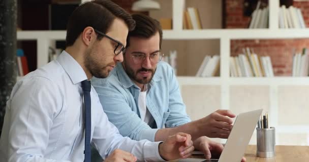 Millennial collega 's zitten op de werkplek bespreken samenwerkingsproject op laptop — Stockvideo