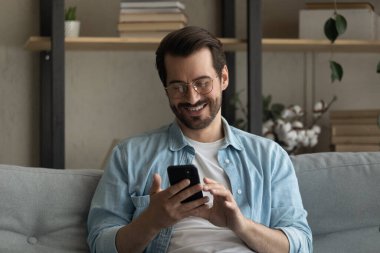 Evde akıllı telefon kullanarak gülümseyen gözlüklü adamı kapat.