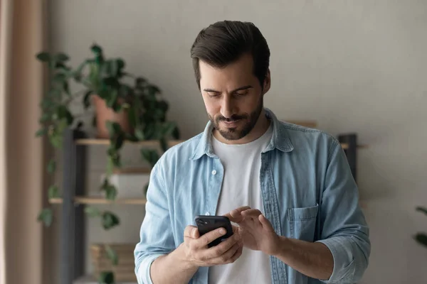 Close up focused man looking at phone screen, standing