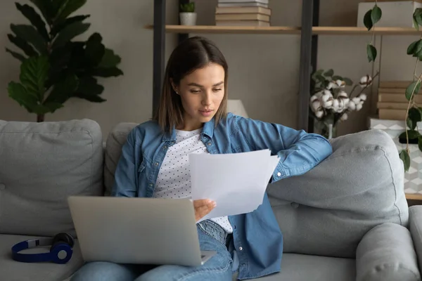 Närbild fokuserad kvinna läsa dokument, med hjälp av laptop hemma — Stockfoto