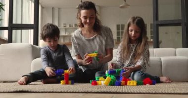Anne ve çocuklar evde renkli plastik bloklar oynuyorlar.