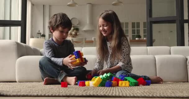 Kleine kinderen spelen thuis kleurrijke plastic blokken — Stockvideo