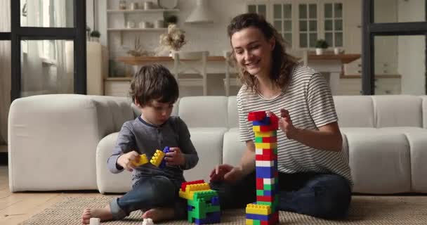 Mama uczy przedszkola syna budować wieżę kolorowego bloku — Wideo stockowe