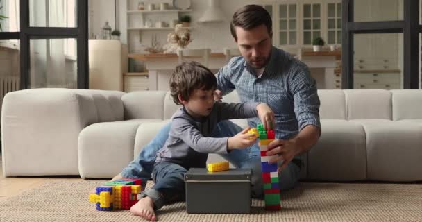 Турботливий тато грає барвисті блоки з маленьким сином — стокове відео