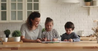 Anne ve çocuklar eskiz defterinde kalemlerle konuşup çiziyorlar.