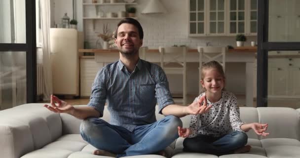 Молодой человек учит маленькую дочь медитировать дома — стоковое видео