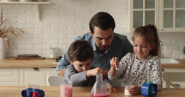Отец и дети играют с наборами для химических экспериментов — стоковое видео