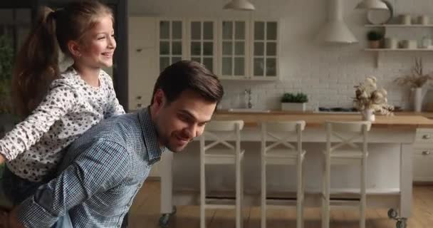 Pai dar passeio de piggyback para pequena filha brincando juntos interior — Vídeo de Stock