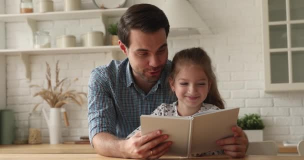 Sevgi dolu baba, küçük kızını bir kitap okurken eğitir. — Stok video