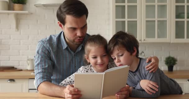Liefdevolle vader die een boek voorleest aan zijn kleine kinderen — Stockvideo