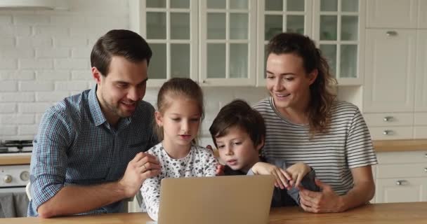 Pareja y los niños se sientan en la cocina se divierten usando la computadora — Vídeos de Stock