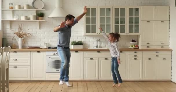 Молодий тато і маленька дочка танцюють на затишній кухні — стокове відео