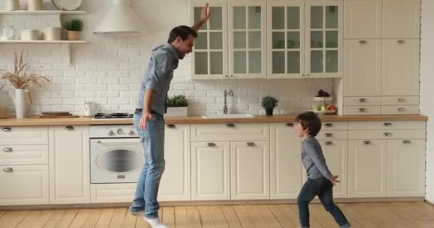 Joven padre e hijo pequeño bailando en la cocina moderna — Vídeos de Stock