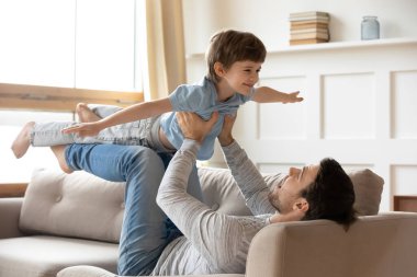 Mutlu genç baba ve küçük oğul evde oynuyorlar.