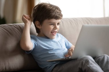 Küçük beyaz çocuk oyun oynarken dizüstü bilgisayar kullanıyor