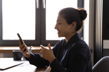 Yandan bakınca gülümseyen Hintli kadın elinde telefonla video görüşmesi yapıyor.