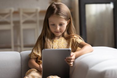 Akıllı küçük kız evde tablet kullanıyor.