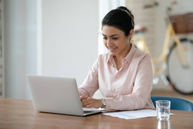 Gülümseyen Hintli kadın çalışan dizüstü bilgisayarda çalışıyor