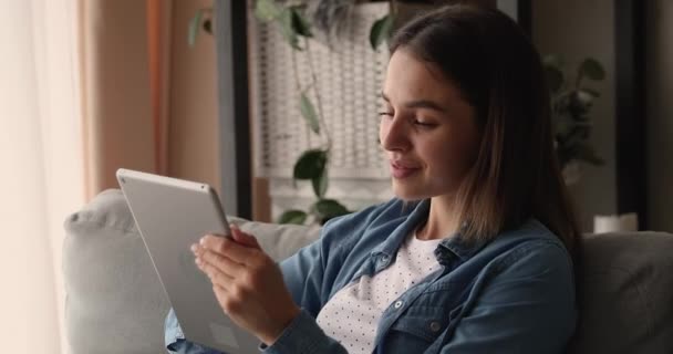 Nainen istuu sohvalla tilalla tabletti laite ostaa Internetistä — kuvapankkivideo