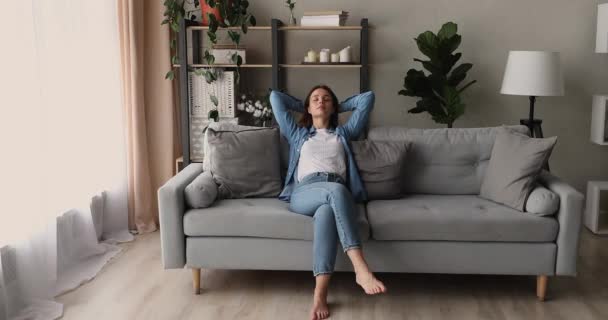Žena dala ruce za hlavu uvolňující na pohodlný gauč — Stock video