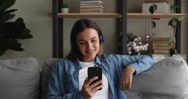 女性は携帯電話を保持するヘッドフォンを着用するビデオ通話会議 — ストック動画