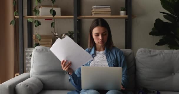 Mulher senta-se no sofá com computador em voltas fazer papelada — Vídeo de Stock