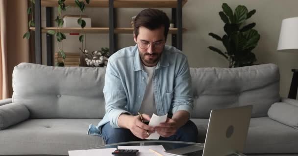 De mens berekent uitgaven op rekenmachine, betaalt rekeningen gebruikend online toepassing — Stockvideo