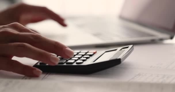 Revisorn sitter vid bordet och arbetar beräknar kostnader med hjälp av räknaren — Stockvideo