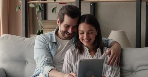 Pareja relajante en sofá pasar el fin de semana utilizando la tableta digital gadget — Vídeo de stock