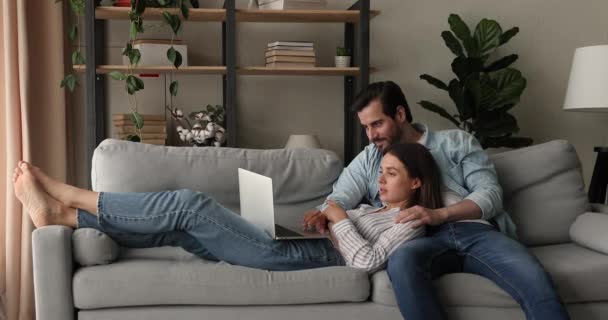Couple relaxant sur canapé dans un salon confortable avec ordinateur portable — Video
