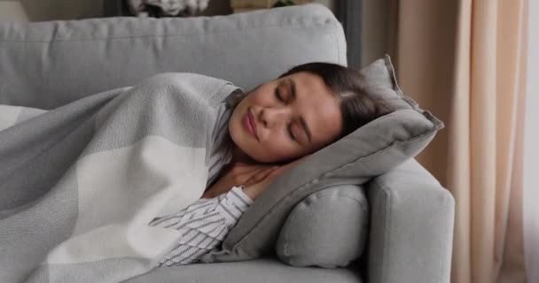 Serene woman sleeping on sofa under plaid in living room — Stock Video