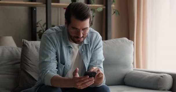 Man sitter på soffan håller smartphone använda mobilapp — Stockvideo