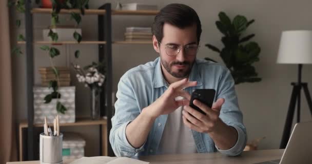 Forretningsmand sidde på arbejdspladsen holder smartphone ved hjælp af mobil applikation – Stock-video