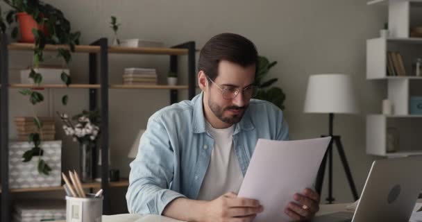 Бизнесмен, сидящий за столом и читающий письма с плохими новостями — стоковое видео