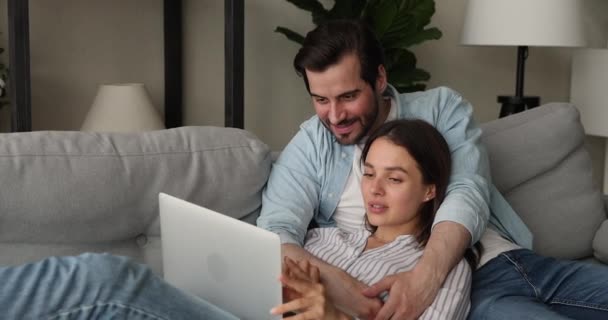 男朋友和女朋友在家里的沙发上用笔记本电脑放松一下 — 图库视频影像