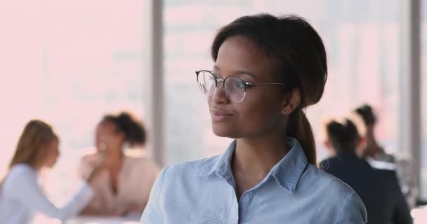 African businesswoman in glasses standing in office looking into distance — Stock Video